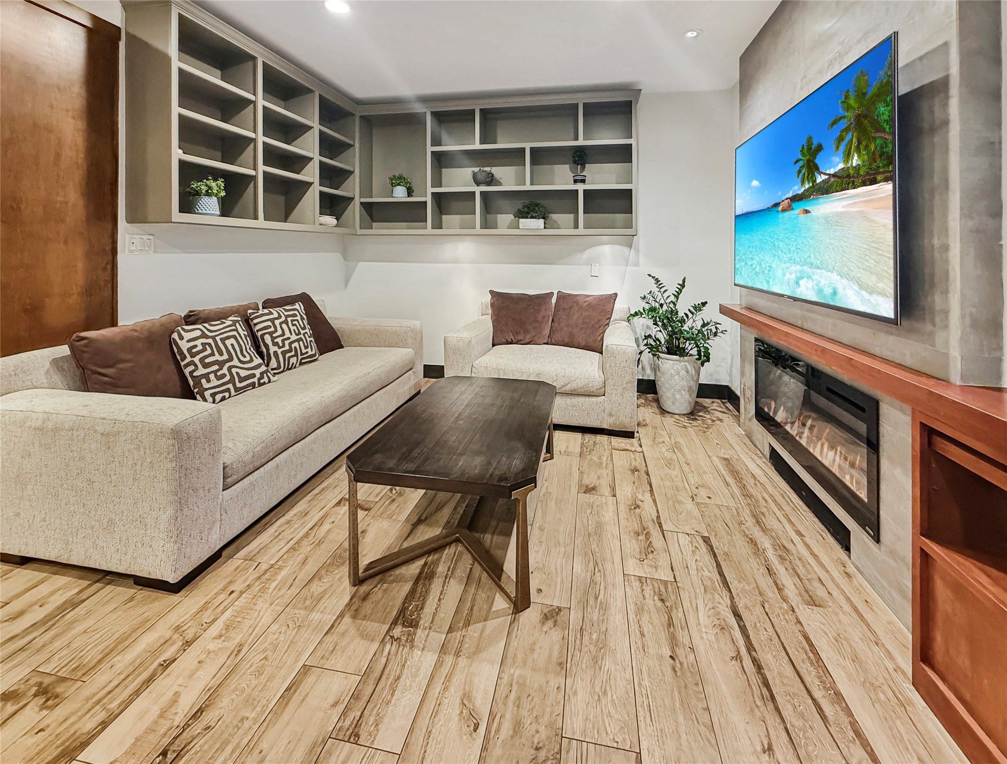 4521 Maple Street Bellaire, TX 77401 - Photo 16 of 36 family room featuring custom built-in shelving and a sleek electric fireplace with media wall. The open layout offers comfortable seating and a clean, modern design ideal for everyday living.