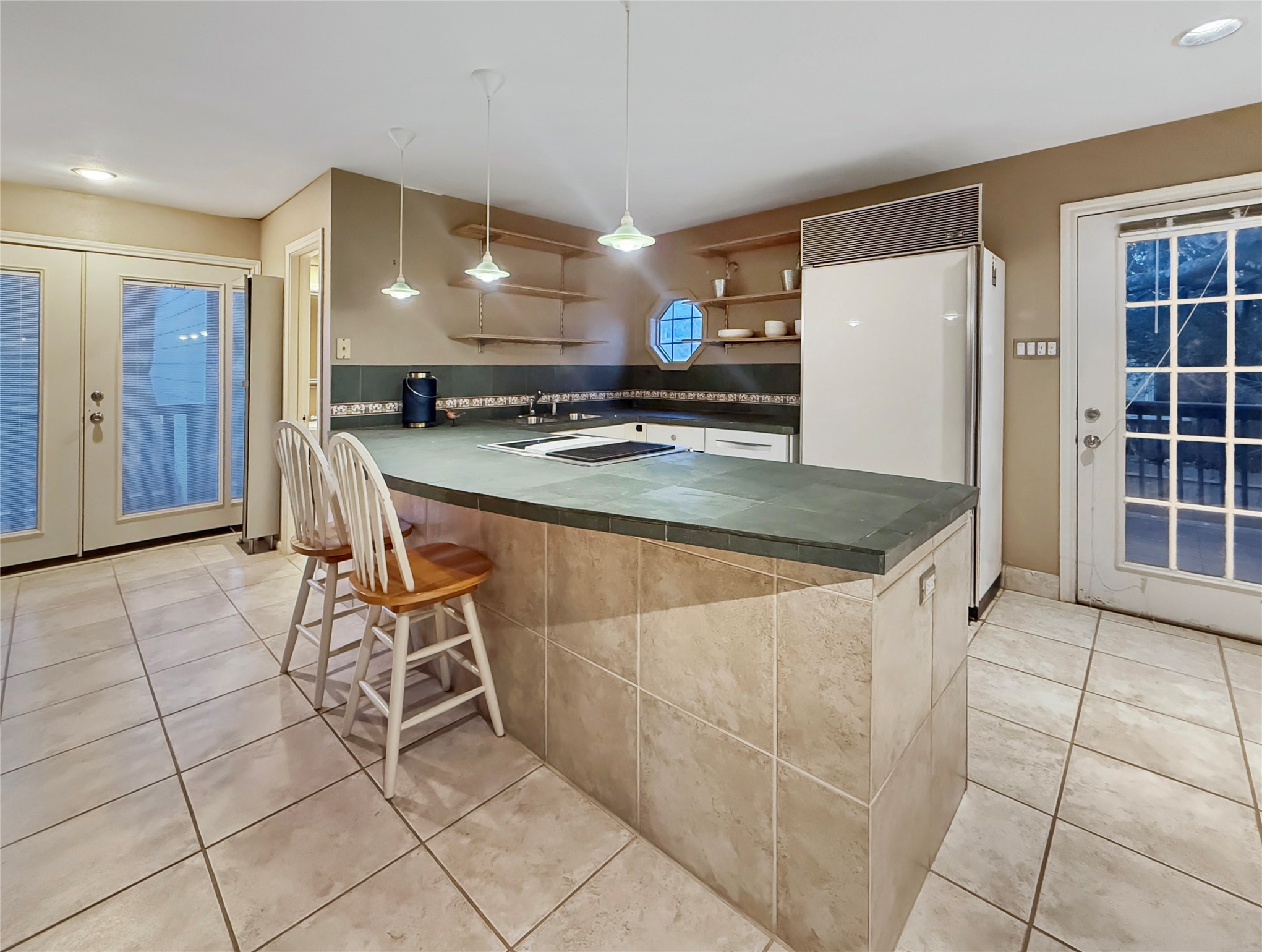 4521 Maple Street Bellaire, TX 77401 - Photo 31 of 36 Kitchenette featuring a full-size Sub-Zero refrigerator, breakfast bar seating, and open shelving for added functionality.