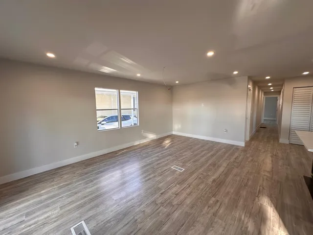 an empty room with wooden floor and windows