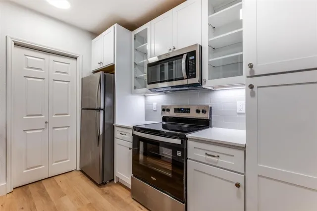 a kitchen with stainless steel appliances white cabinets white stove a microwave and a refrigerator