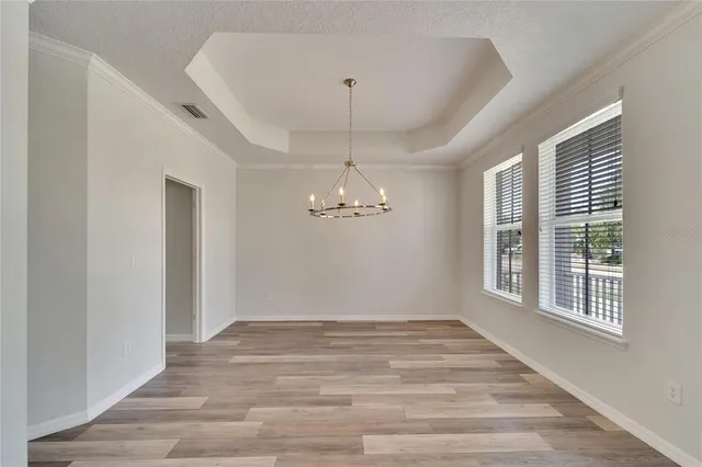a view of an empty room with wooden floor and window