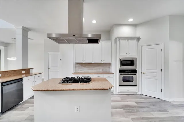 an empty room with chandelier fan and windows