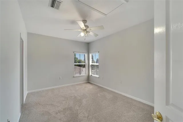 a view of an empty room with chandelier fan and a window
