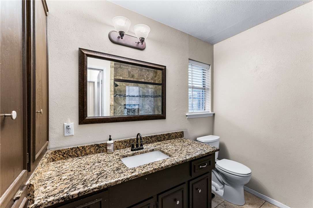 4325 St George Drive Corpus Christi, TX 78413 - Photo 7 of 22 a bathroom with a granite countertop toilet sink and mirror