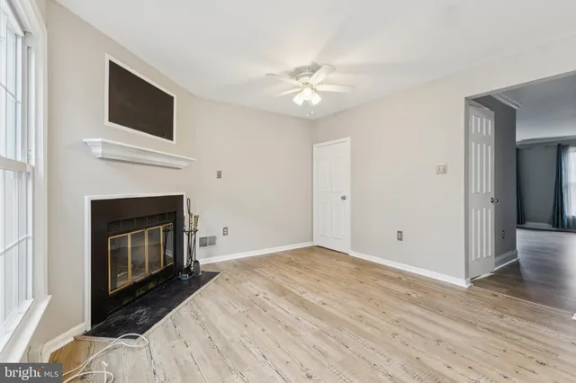a view of an empty room with wooden floor fireplace and a window