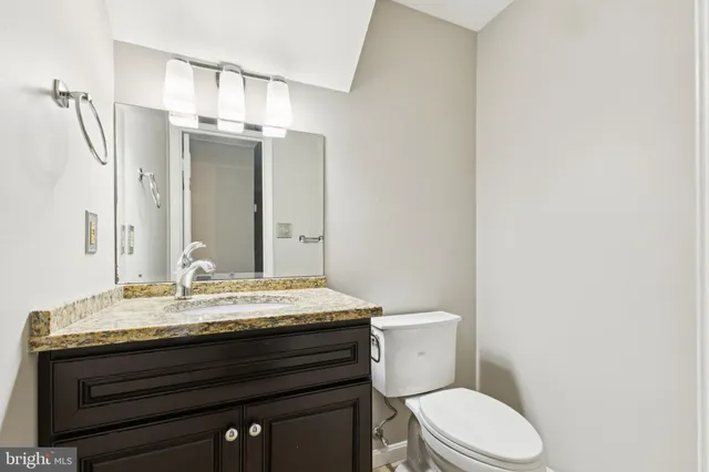 a bathroom with a granite countertop bathtub sink vanity mirror and toilet