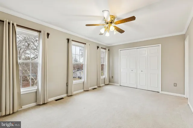 a view of an empty room with window and closet area