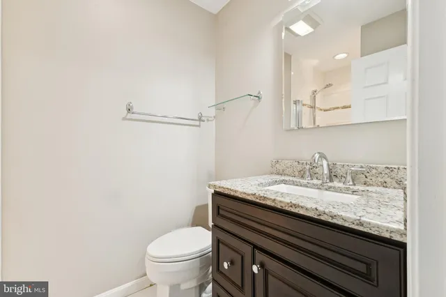 a bathroom with a granite countertop toilet sink and mirror