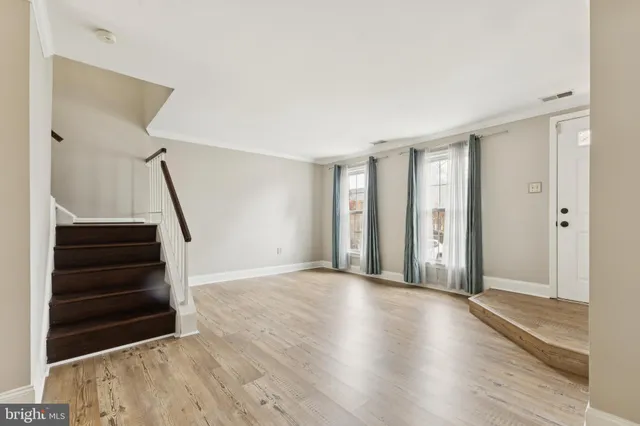 a view of a livingroom with wooden floor and stairs