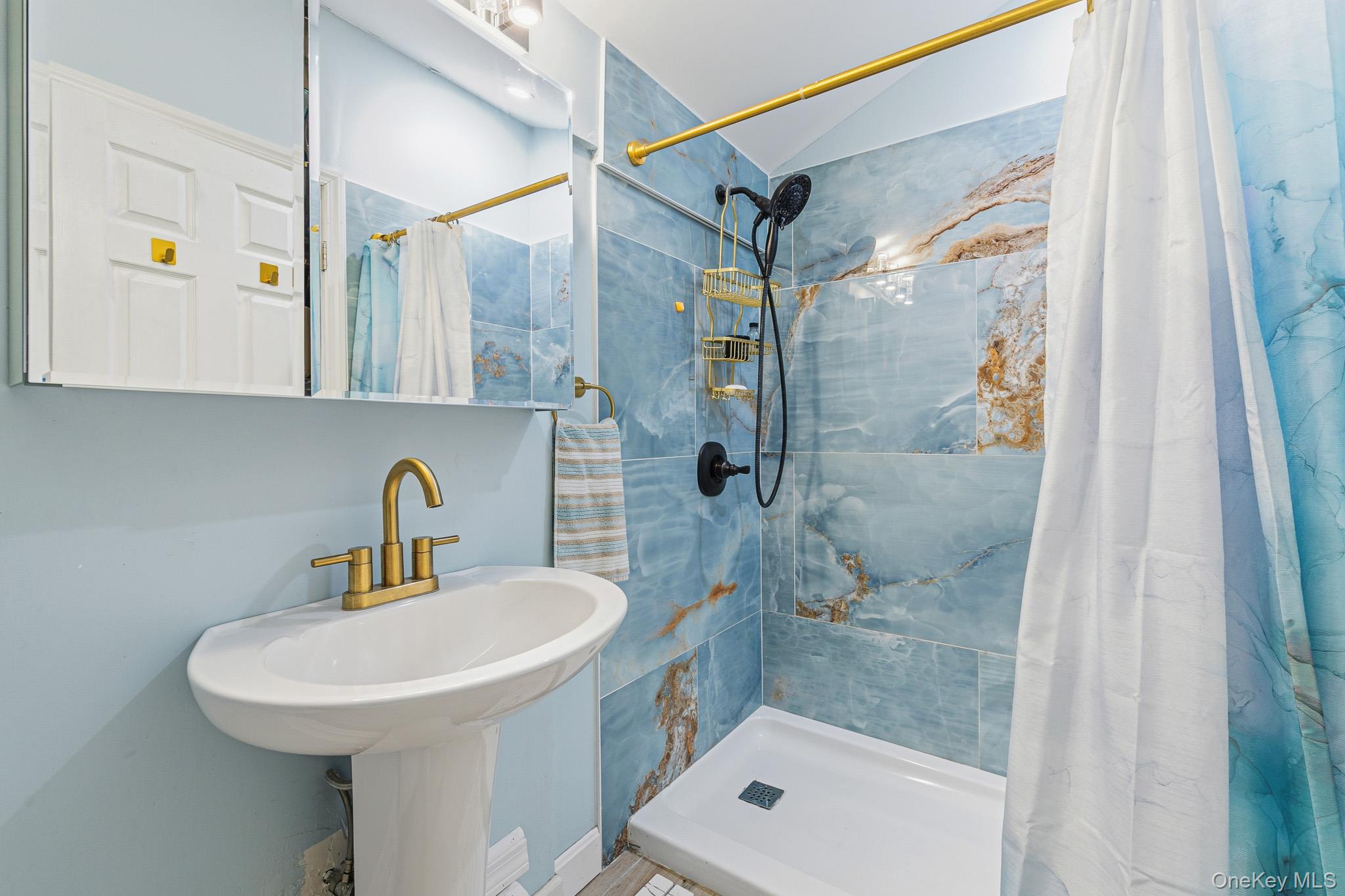 33 Lillian Road Nesconset, NY 11767 - Photo 27 of 42 The Beautifully Renovated Primary Bathroom Offers An Oversized Custom Shower With Stunning 24" x 48" Porcelain Tiled Walls, Pedestal Sink, Plank Tiled Floors & All Upgraded Fixtures.