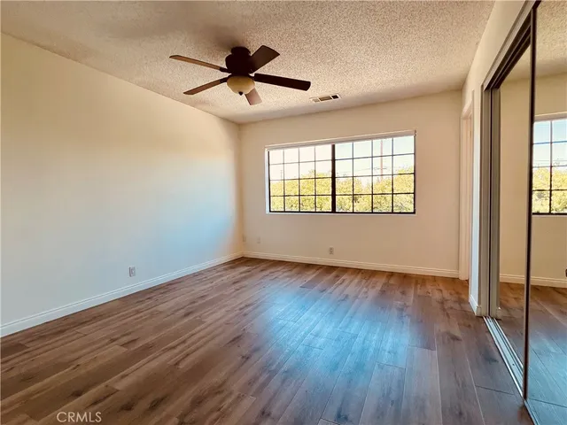 a view of empty room with wooden floor and fan