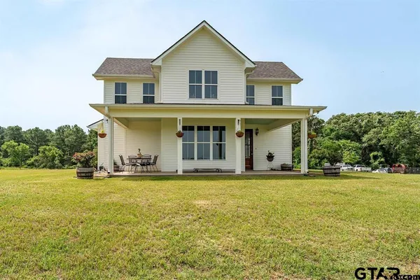 a view of a white house with a big yard and large trees