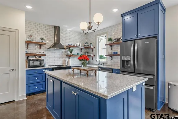a kitchen with stainless steel appliances granite countertop a sink a refrigerator and a wooden cabinets