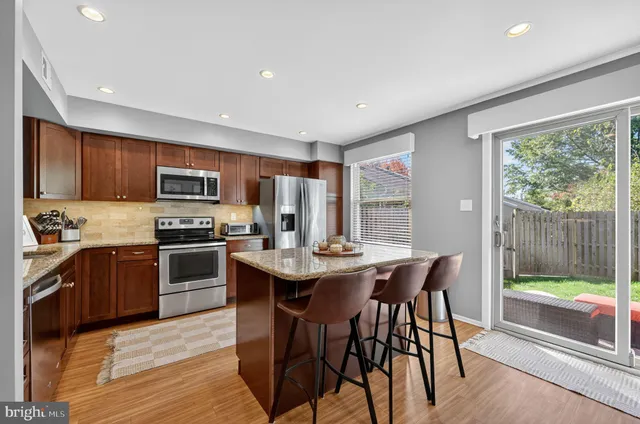 a kitchen with stainless steel appliances granite countertop a stove top oven a sink dishwasher a dining table and chairs with wooden floor