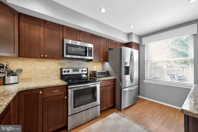 a kitchen with granite countertop wooden cabinets stainless steel appliances and a window