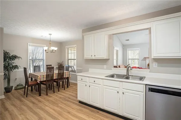 a kitchen with cabinets a sink dishwasher a dining table and chairs with wooden floor