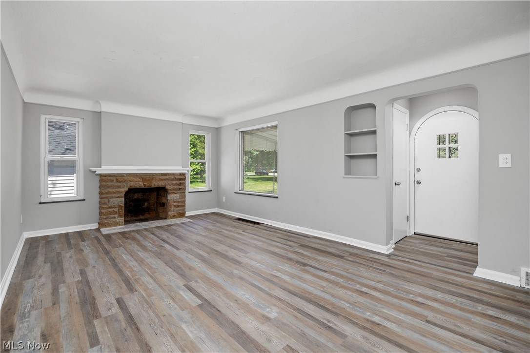 7030 Pearl Road Cleveland, OH 44130 - Photo 15 of 34 Unfurnished living room featuring a stone fireplace, hardwood / wood-style flooring, and built in shelves