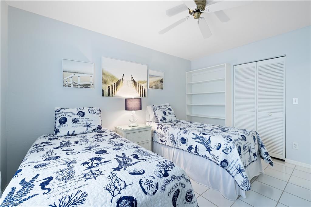 565 Beachwalk Circle, Unit T102 Naples, FL 34108 - Photo 16 of 33 a bedroom with two beds and a chandelier