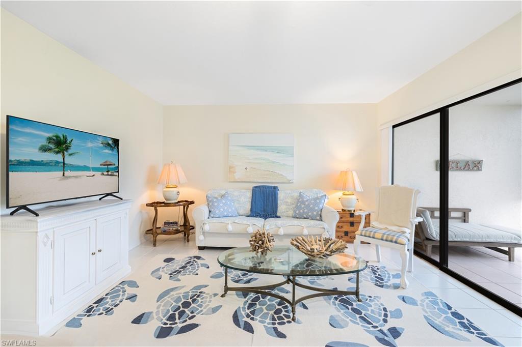 565 Beachwalk Circle, Unit T102 Naples, FL 34108 - Photo 2 of 33 a living room with furniture a flat screen tv and a large window