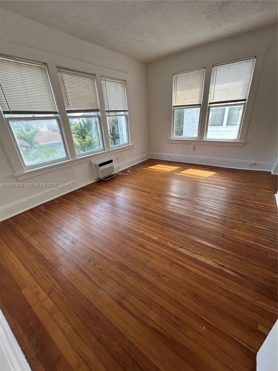 529 Northeast 66th Street, Unit 8 Miami, FL 33138 - Photo 2 of 5 an empty room with wooden floor and windows