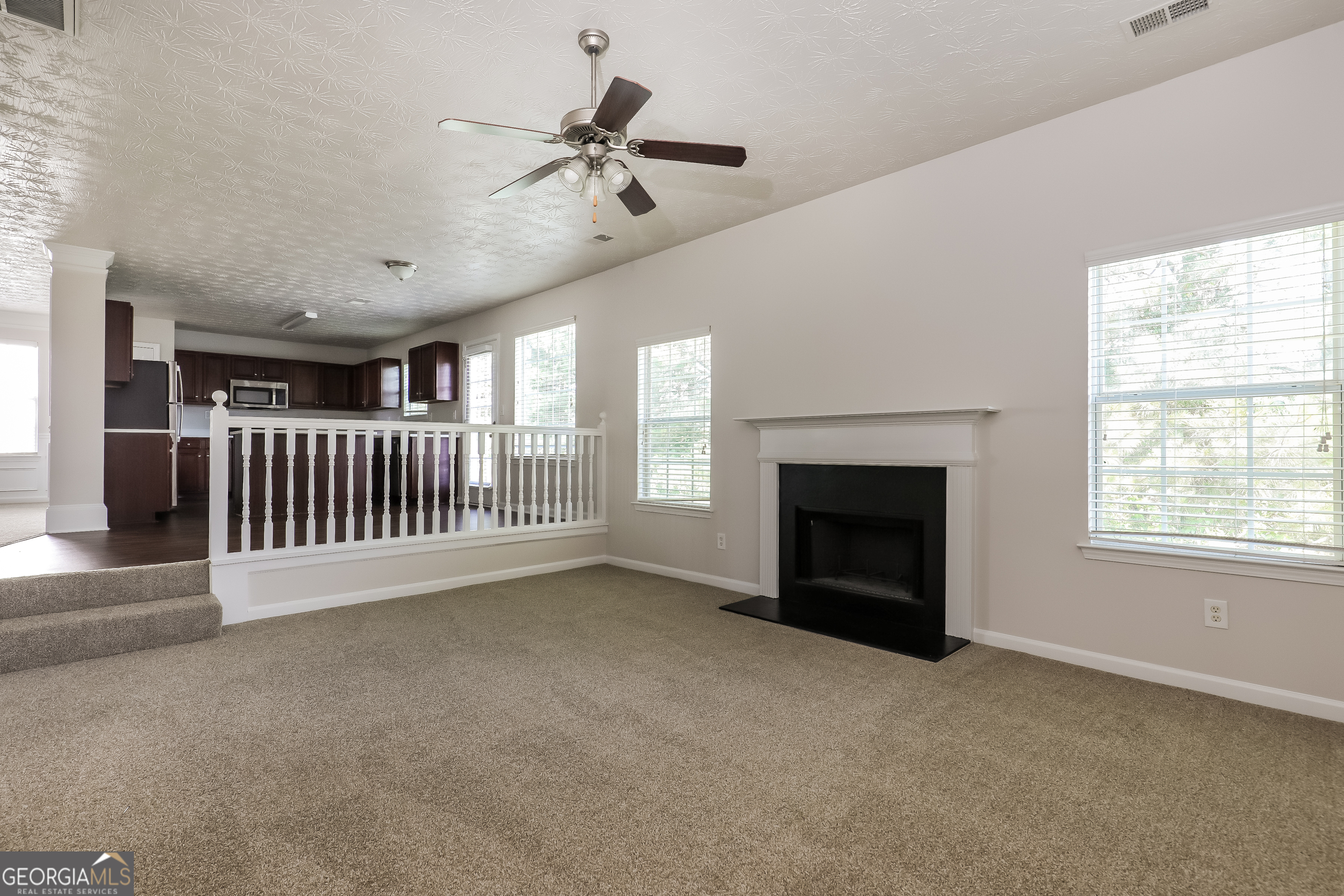 7812 Bell Tower Lane Fairburn, GA 30213 - Photo 3 of 17 a view of a livingroom with a fireplace a ceiling fan and windows