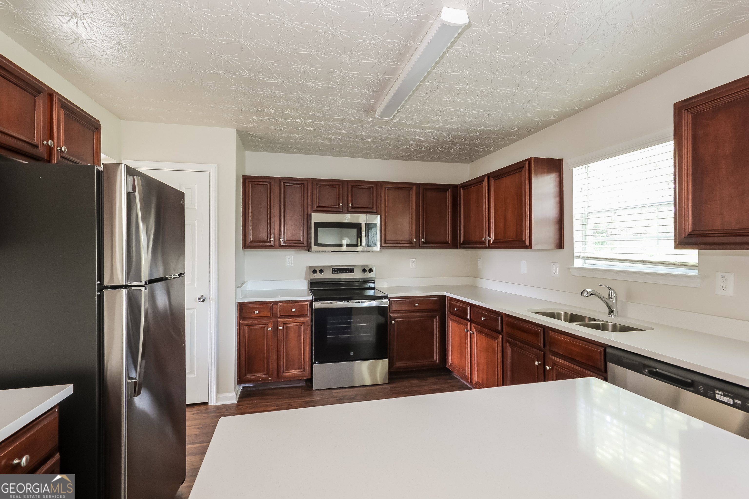 7812 Bell Tower Lane Fairburn, GA 30213 - Photo 6 of 17 a kitchen with stainless steel appliances granite countertop a refrigerator a sink a stove a microwave and wooden cabinets
