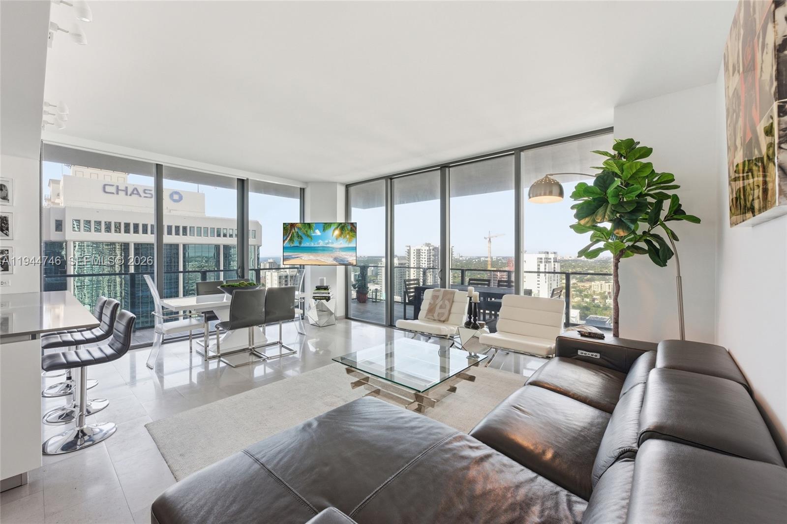 88 Southwest 7th Street, Unit 2302 Miami, FL 33130 - Photo 6 of 43 a living room with furniture large windows and a potted plant