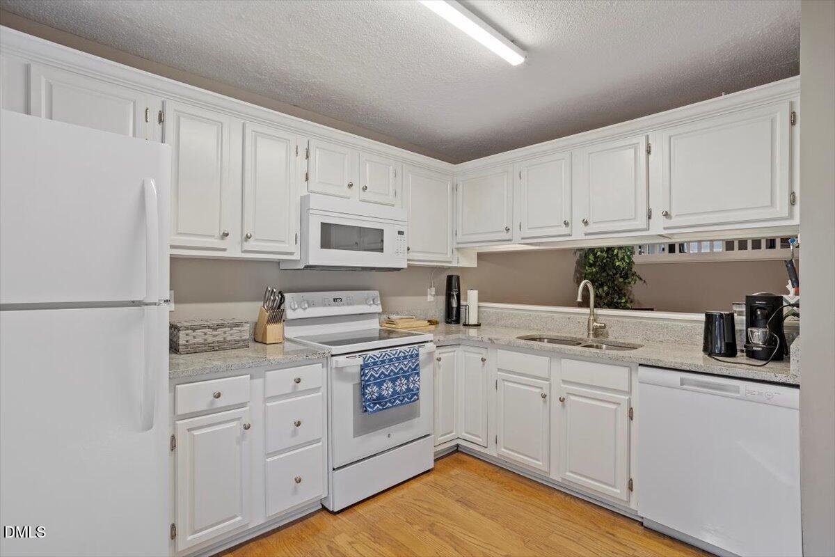 100 Hunting Chase, Unit 1D Cary, NC 27513 - Photo 11 of 33 a kitchen with white cabinets and white appliances
