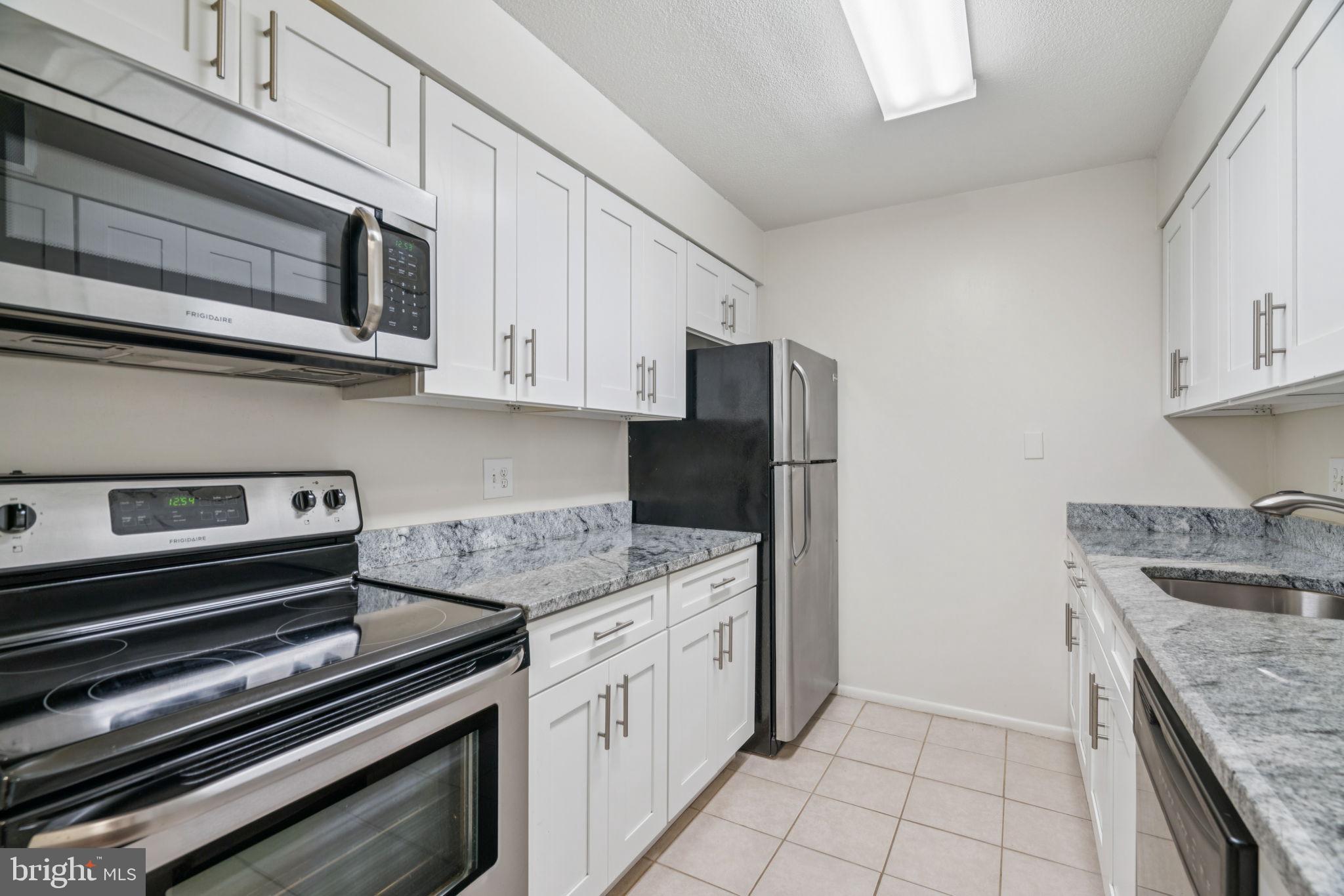 1420 Locust Street, Unit 28P Philadelphia, PA 19102 - Photo 8 of 25 a kitchen with stainless steel appliances granite countertop a stove microwave and refrigerator