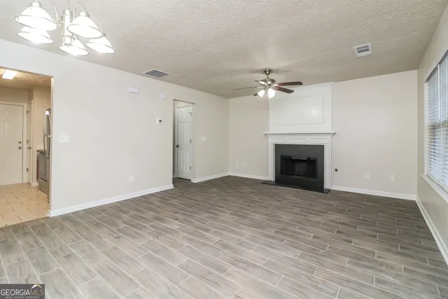 an empty room with fan and a fireplace