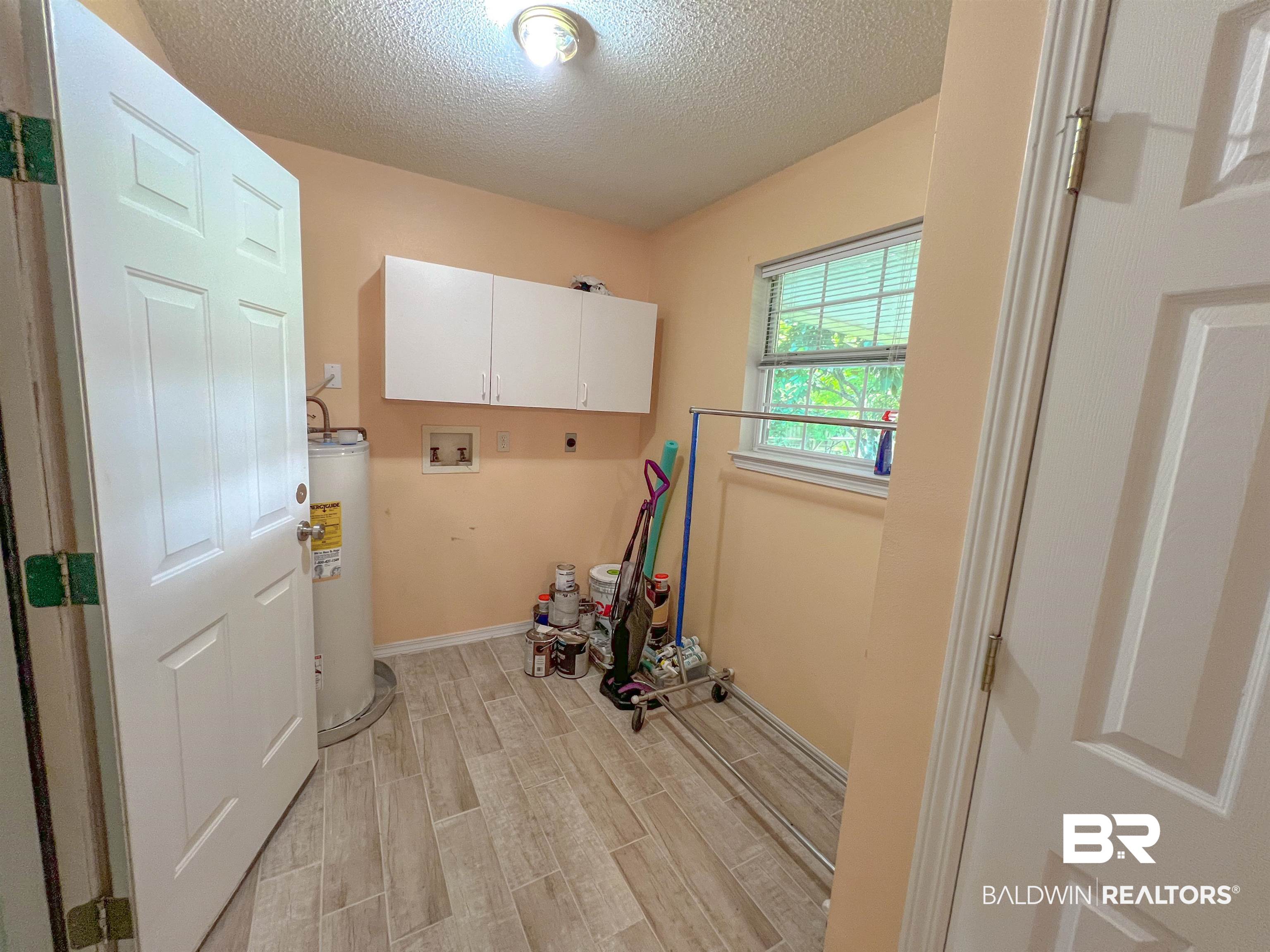 1200 South Juniper Street Foley, AL 36535 - Photo 5 of 23 Laundry room featuring hookup for a washing machine, cabinets, hookup for an electric dryer, a textured ceiling, and gas water heater