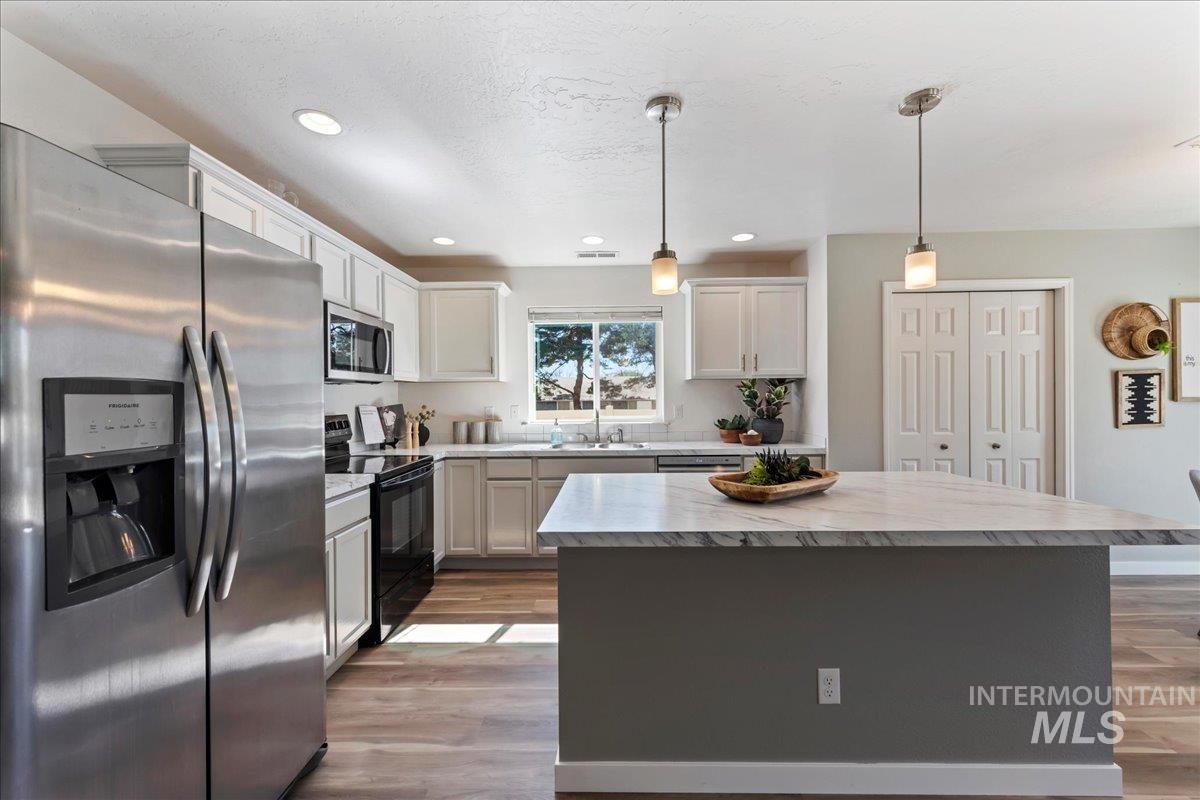 777 South Flintstone Avenue Meridian, ID 83642 - Photo 12 of 38 Kitchen with stainless steel appliances, a kitchen island, light countertops, hanging light fixtures, and dark wood-style flooring