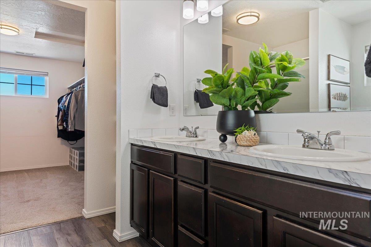777 South Flintstone Avenue Meridian, ID 83642 - Photo 20 of 38 Bathroom featuring a walk in closet, double vanity, dark wood-style flooring, and a textured ceiling