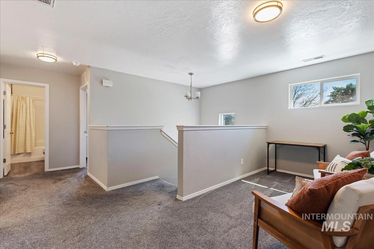 777 South Flintstone Avenue Meridian, ID 83642 - Photo 26 of 38 Living area with carpet floors, a textured ceiling, an upstairs landing, and suspended lighting