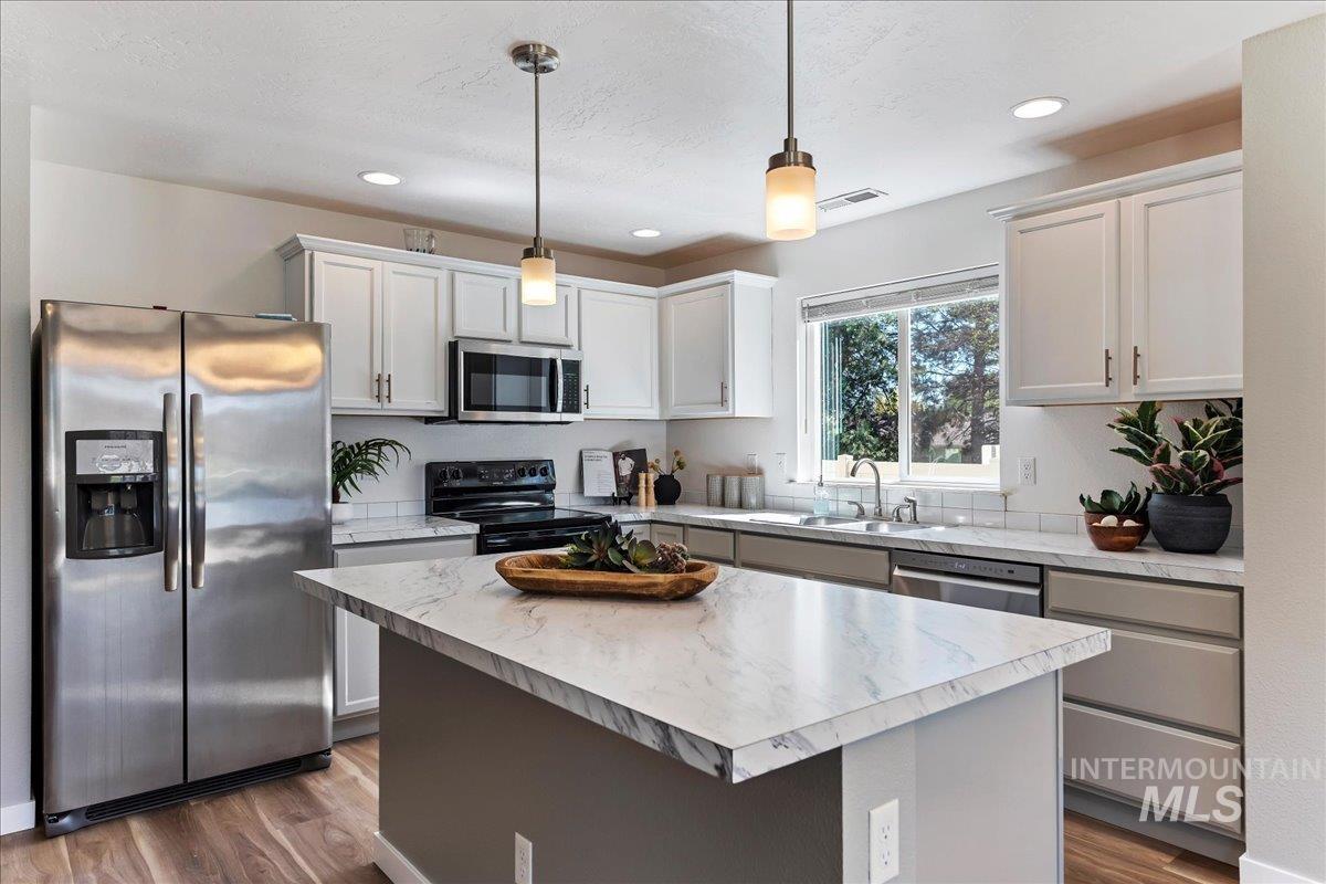 777 South Flintstone Avenue Meridian, ID 83642 - Photo 4 of 38 Kitchen featuring stainless steel appliances, light countertops, a kitchen island, and dark wood-style floors
