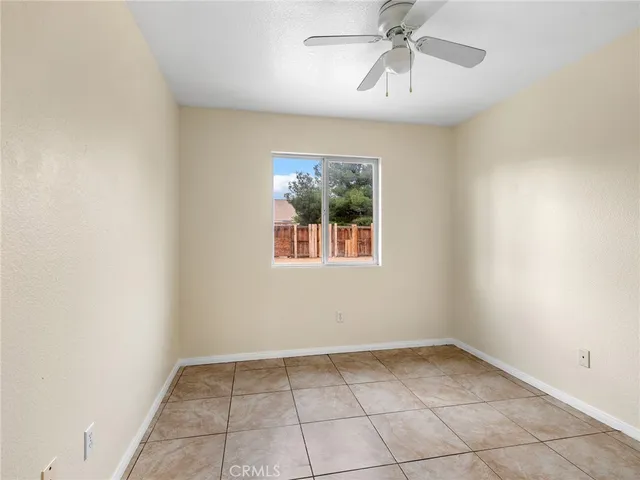 an empty room with chandelier fan and windows