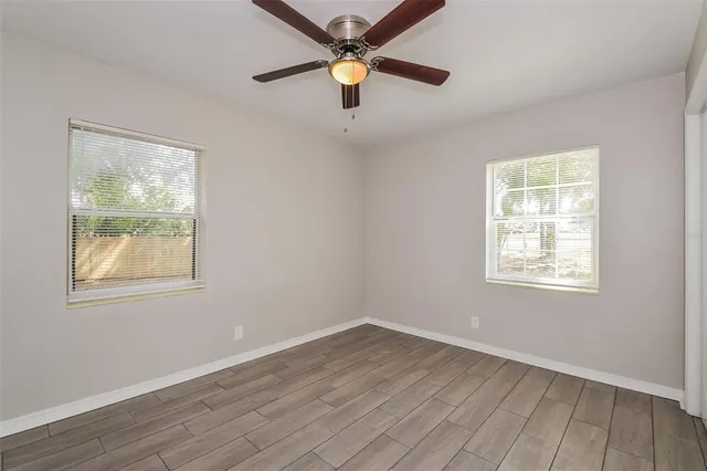 a view of an empty room with window and wooden floor