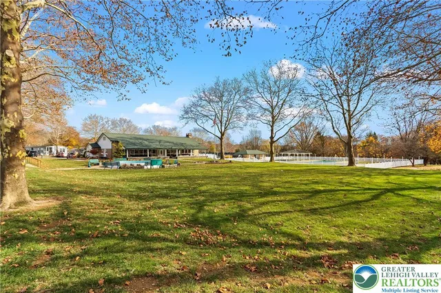 a view of swimming pool with outdoor seating and trees in the background