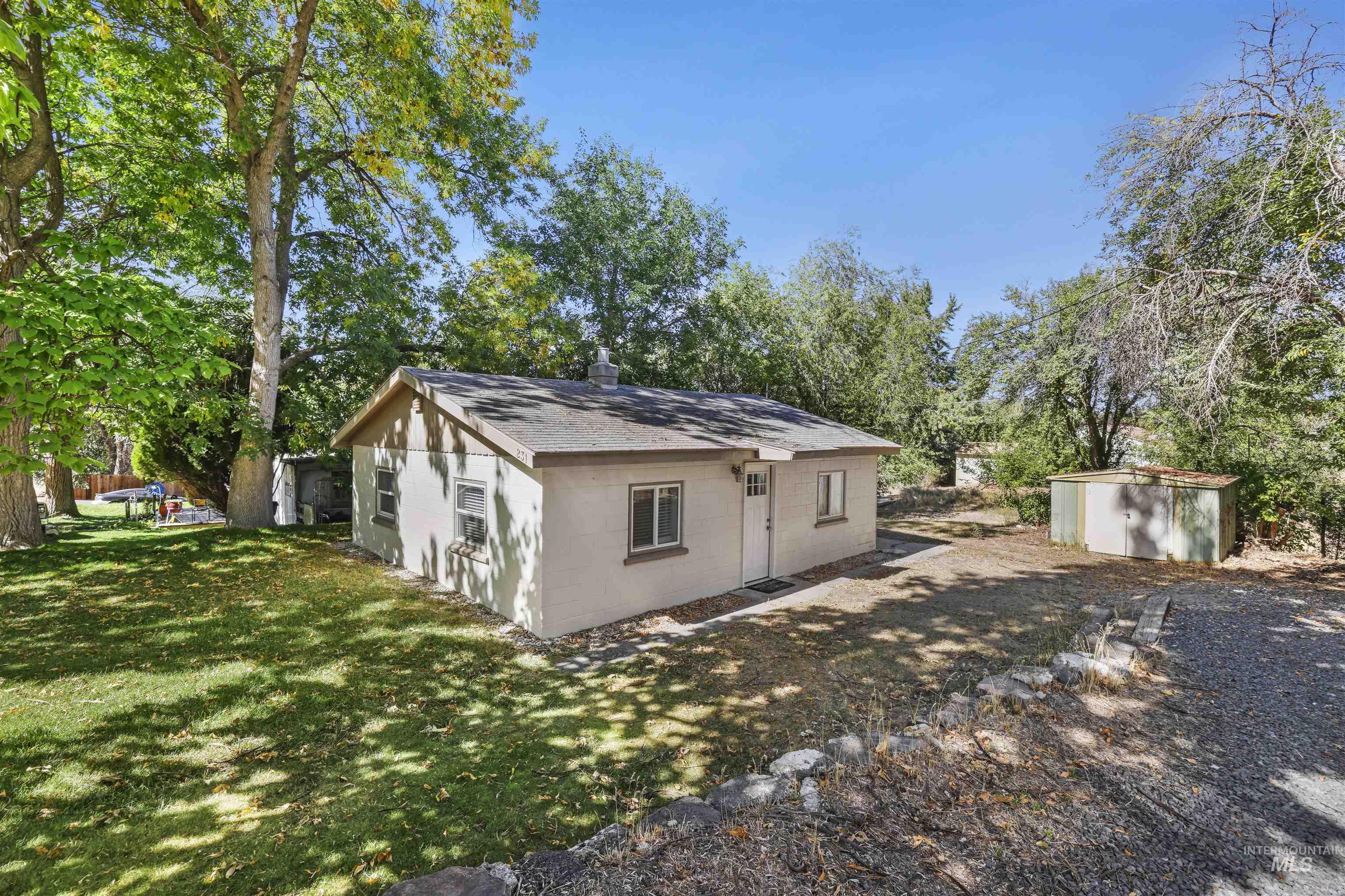 Rear view of property with concrete block siding, a yard, a storage unit, and view of scattered trees