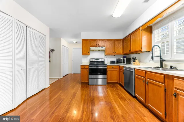 a kitchen with wooden floors appliances a window and a sink