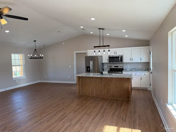 a kitchen with stainless steel appliances kitchen island granite countertop a stove a sink and a refrigerator