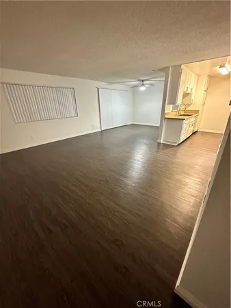 an empty room with wooden floor and windows with curtains
