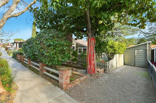 a view of a house with a tree and wooden fence