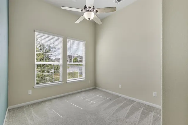 an empty room with chandelier fan and windows