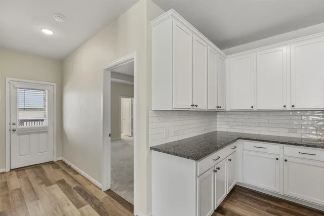 a kitchen with granite countertop white cabinets and sink