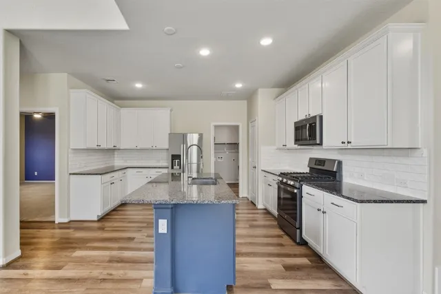 a large kitchen with stainless steel appliances lots of counter space and wooden floor