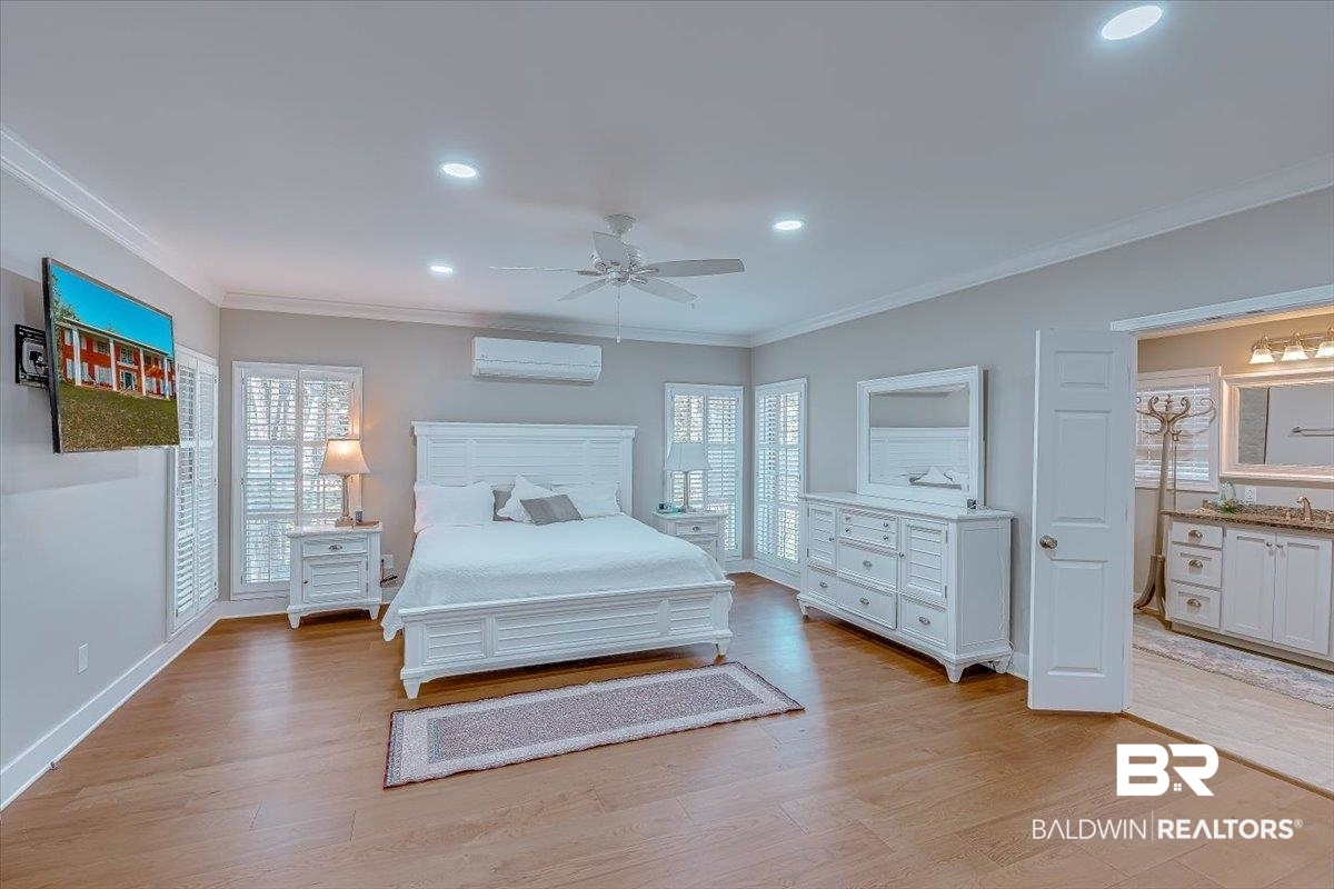 14160 Moffett Road Wilmer, AL 36587 - Photo 22 of 75 Bedroom featuring multiple windows, light wood-style flooring, an AC wall unit, and crown molding