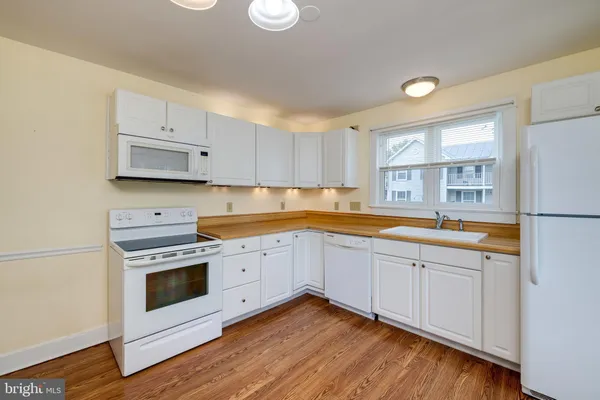 a kitchen with granite countertop white cabinets and white appliances