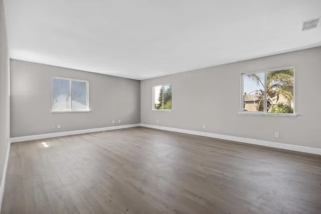 a view of an empty room with a window and wooden floor
