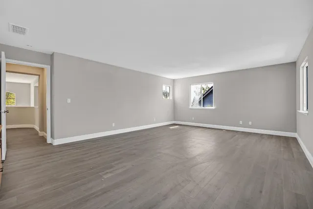 a view of an empty room with wooden floor and window